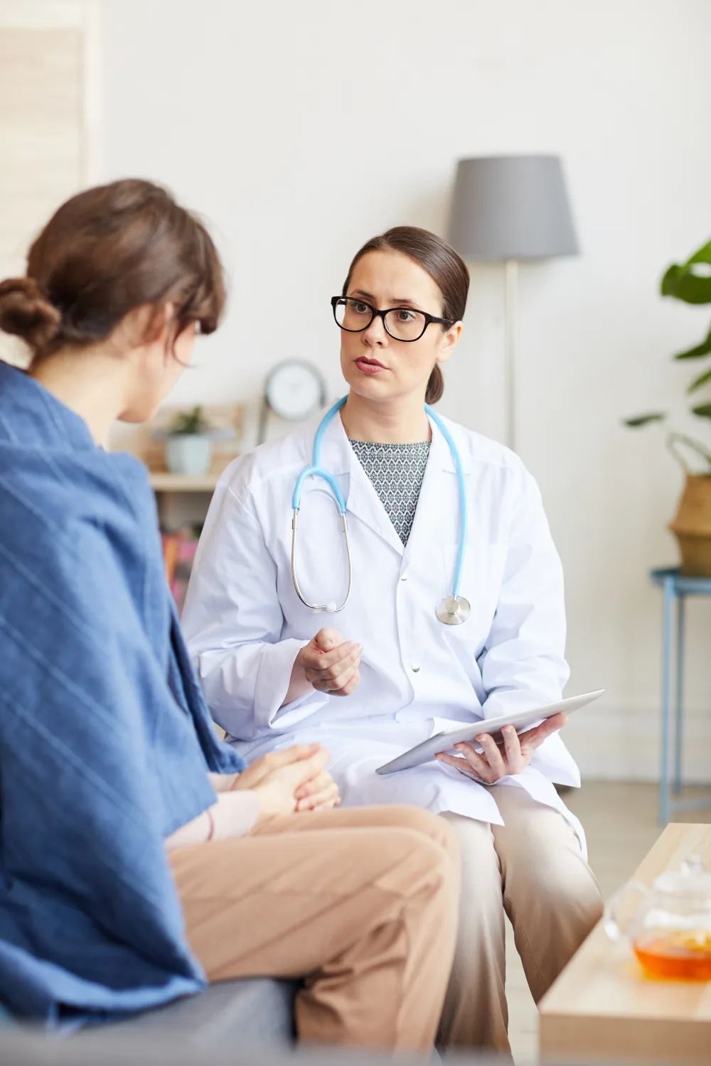 A patient in conversation with a practitioner in a light-filled consultation room
